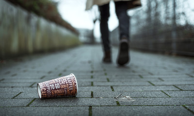 Mann wirft leeren Kaffeebecher auf Gehweg