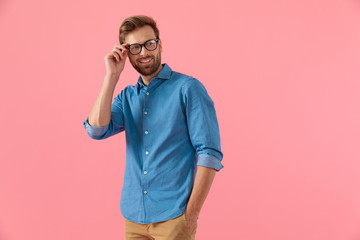 happy casual guy looking to side and fixing glasses