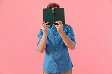 casual guy in denim shirt hiding behind book
