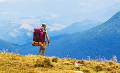 Hiker with big backpack on blue mountains background_