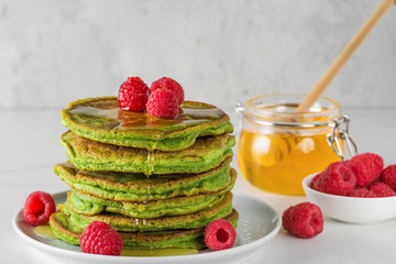 Matcha tea green pancakes. Pile of homemade pancakes with fresh raspberries and honey. healthy breakfast dessert