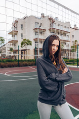 Fototapeta premium a girl with a carefully serious look stands arms crossed on her chest on a sports court