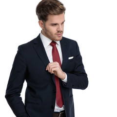 confident young businessman in suit arranging coat