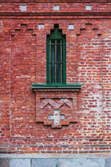 Old Orthodox church facade made of red bricks, visible cross and ornaments on the wall
