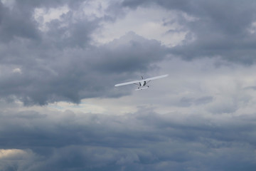 Fototapeta na wymiar Yaslo, Poland - july 1 2018: A light sport turboprop aircraft flies across the sky among the rainy clouds. Landing in difficult weather conditions. Meteorology and weather forecast for aviation