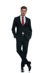 confident young businessman in suit holding hands in pockets