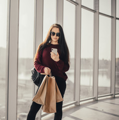 Young brunette woman with shopping bags in city mall waiting for friend