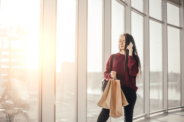 Young brunette woman with shopping bags in city mall waiting for friend
