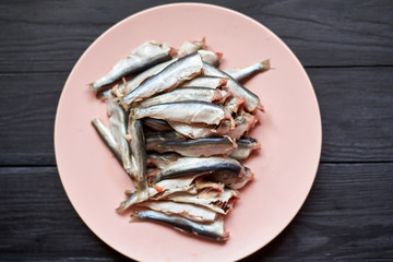 Raw gutted fish sprats, herring on a plate on a wooden background.
