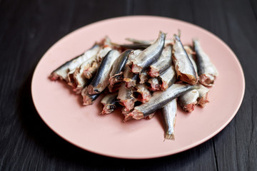 Raw gutted fish sprats, herring on a plate on a wooden background.