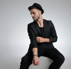 cool fashion guy wearing hat and holding elbow in a fashion pose