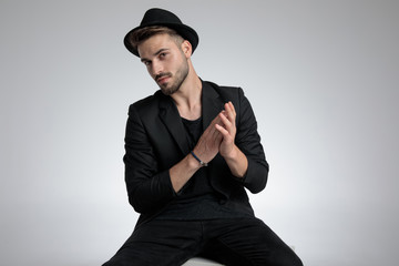 cool young man in black coat touching palms