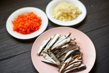 Raw herring fish, sprats and chopped onions and carrots. Preparation for cooking fish with...