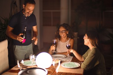 Beautiful family dinning, drinking cup of wine smiling at terrace