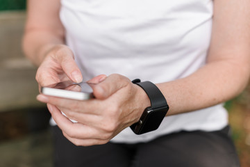 Female hiker using smartphone and smart watch while resting