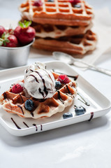 waffle and berry ice cream, strawberries, blueberries. served on a white plate and on a white table