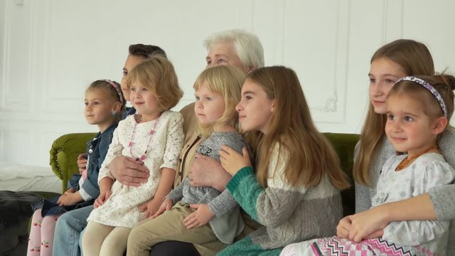 Photographer is taking pictures of an elderly white-haired woman with her seven grandgrandchildren. The beautiful multi-generations family enjoys togetherness 