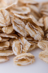 raw oat flakes on white acrylic background