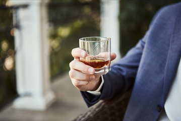 Businessman holding a glass of whisky, close up. Tasting and degustation concept. Place for text