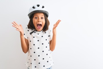 Beautiful child girl wearing security bike helmet standing over isolated white background...