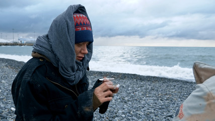 homeless couple, man and woman smoking on the seashore
