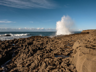 Water splash on a sunny day, Wave hits stone coast line, West of Ireland. Blue clear sky, Sumner time.