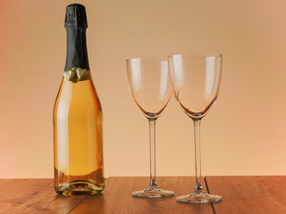 Champage bottle decorated for Saint Valentine day with two golden hearts and two glasses on a wooden surface, Warm tones.