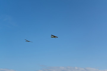 Plane pulling glider. White clouds in background. Self propelled glider in air. Plane dragging the glider.