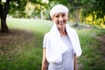 Portrait of smiling sporty senior woman with towel outdoor - Powered by Adobe