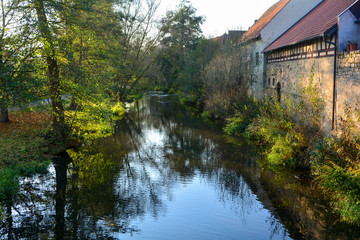 Fototapeta premium Creek with nature and old houses in the evening light,with reflection