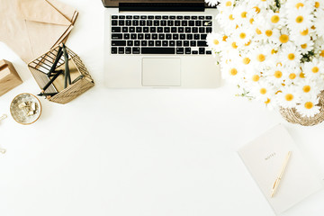 Home office desk workspace with laptop, chamomile daisy flowers bouquet and notebook on white background. Flat lay, top view minimal freelancer work concept with copy space mockup.