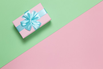 Pink gift box with blue bow on pastel two-color background pink and green, copy space, flat lay. March 8, February 14, birthday, St. Valentine's, Mother's, Women's day celebration concept. Horizontal