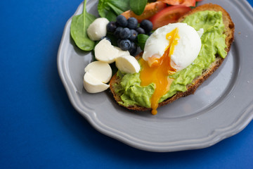 Wholesome tasty full of vitamins and health breakfast with avocado, berries, cheese and tomatoes with basil.