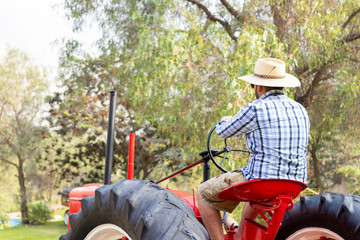 Handsome man with sunglasses driving the tractor to work on the farm