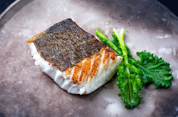 Gebratenes europäisches Skrei Kabeljau Fisch Filet mit Stängelkohl als closeup auf einem Modern...