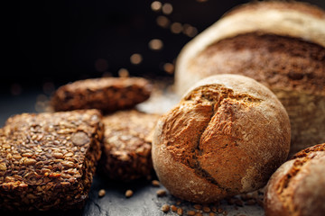 Wholemeal bread,  rolls and bread on a black background, close up