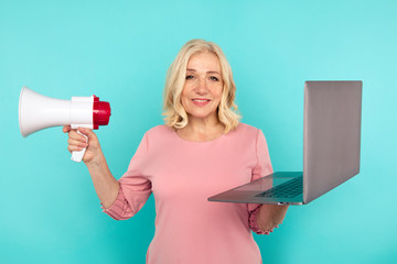 Woman with laptop and loudspeaker standing isolated over the blue studio