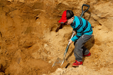 Digging a hole in the sand with a shovel. Sand for construction. The boy helps.
