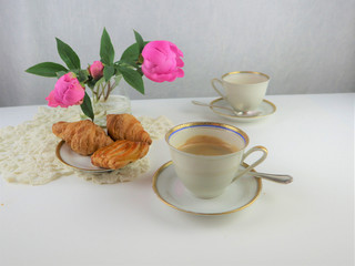 breakfast with two cups of coffee and croissants, pink flowers