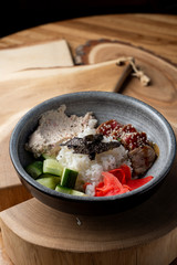 Tuna poke bowl with white rice, ginger and cucumber on wooden rustic table