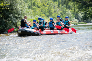 Rafting team goes down the river on the beautiful sunny day.