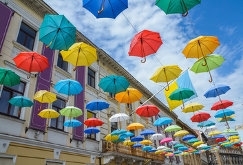 Street decoration, lots of colorful umbrellas in the air over old building and sky, Lviv, Ukraine