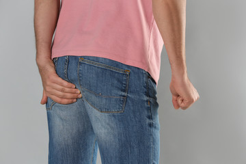 Man suffering from hemorrhoid on light grey background, closeup