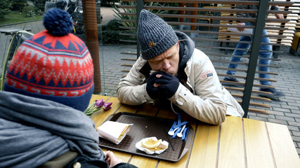 homeless couple, man and woman eating leftovers from a table in a street cafe