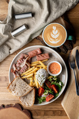 Substantial breakfast in a cafe with bacon, roasted sausage poached egg and salad