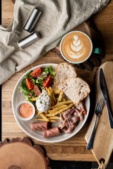 Substantial breakfast in a cafe with bacon, roasted sausage poached egg and salad