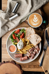 Substantial breakfast in a cafe with bacon, roasted sausage poached egg and salad