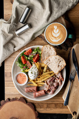 Substantial breakfast in a cafe with bacon, roasted sausage poached egg and salad