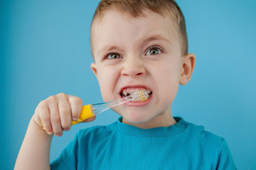 Little cute boy brushing his teeth on blue background