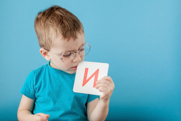 Cute little boy with letter on blue background. Child learning a letters. Alphabet